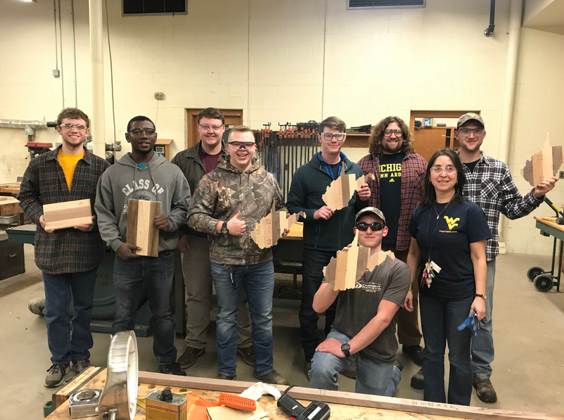 Wood Science and Technology students holding hand-made pieces in wood shop.